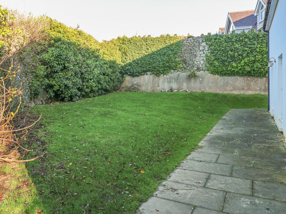 A garden with grass and a paved pathway next to a building at Cambrie in Tenby
