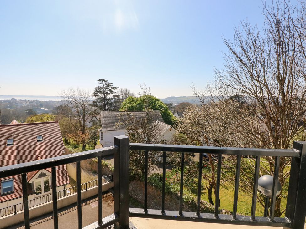 A view from a balcony with black railings overlooking houses trees and distant hills at Cambrie in Tenby