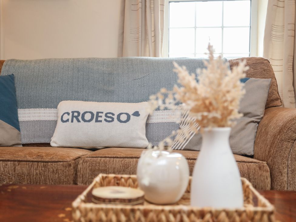 A living room with a brown sofa cushions and a woven tray with decorative items on a wooden table at Bwthyn Derwin Fawr in Garndolbenmaen near Penygroes