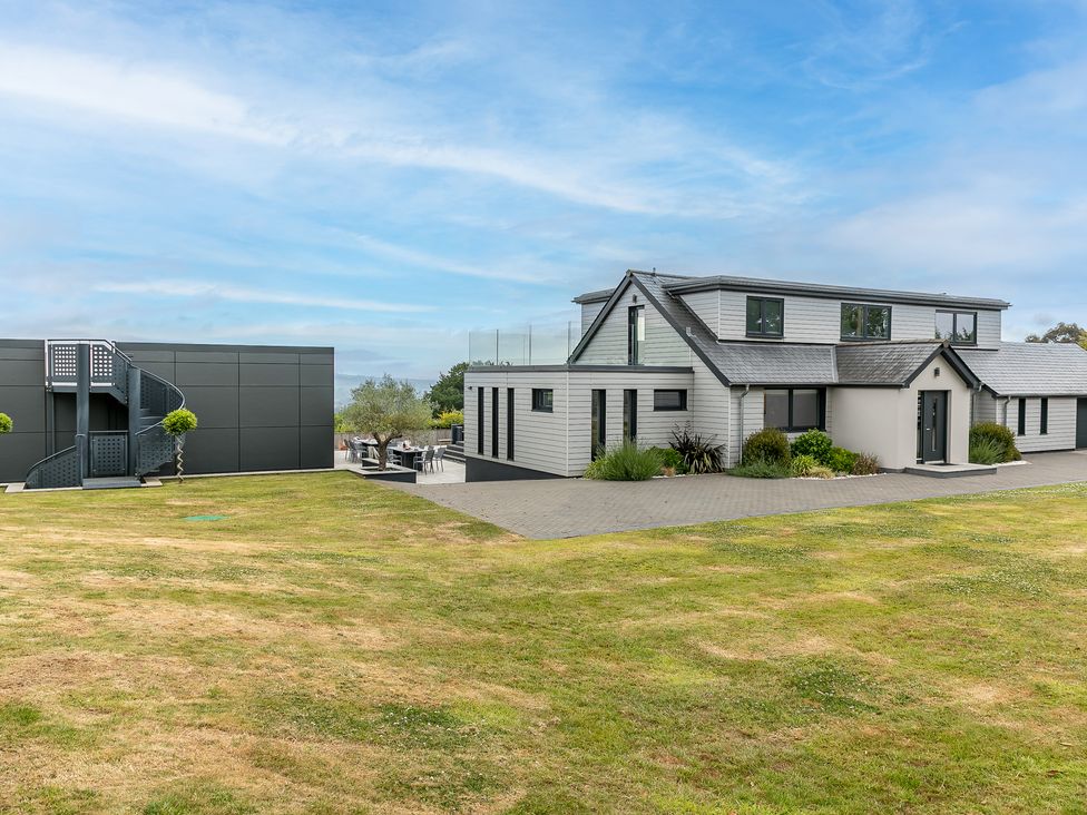 A modern house with a spiral staircase and lawn at Huxham View and Annex in Stoke Canon