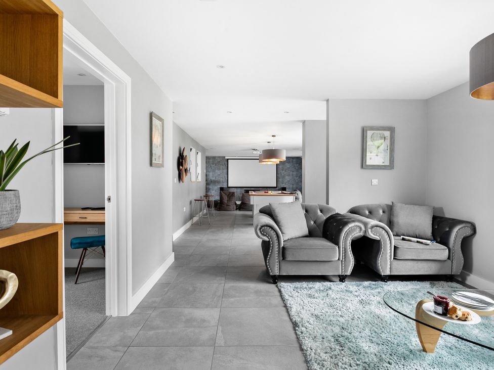 A lounge area with two armchairs and a glass coffee table with snacks on a rug at Huxham View and Annex in Stoke Canon