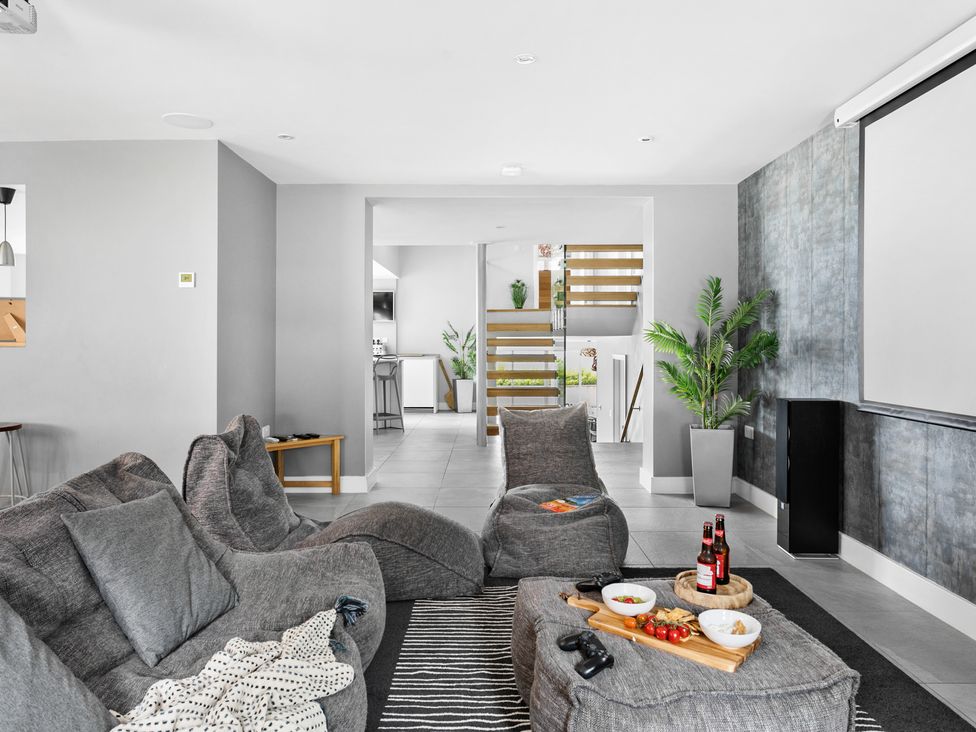 A living room with gray bean bag chairs and pillows a small table with snacks and drinks and a staircase in the background at Huxham View and Annex in Stoke Canon