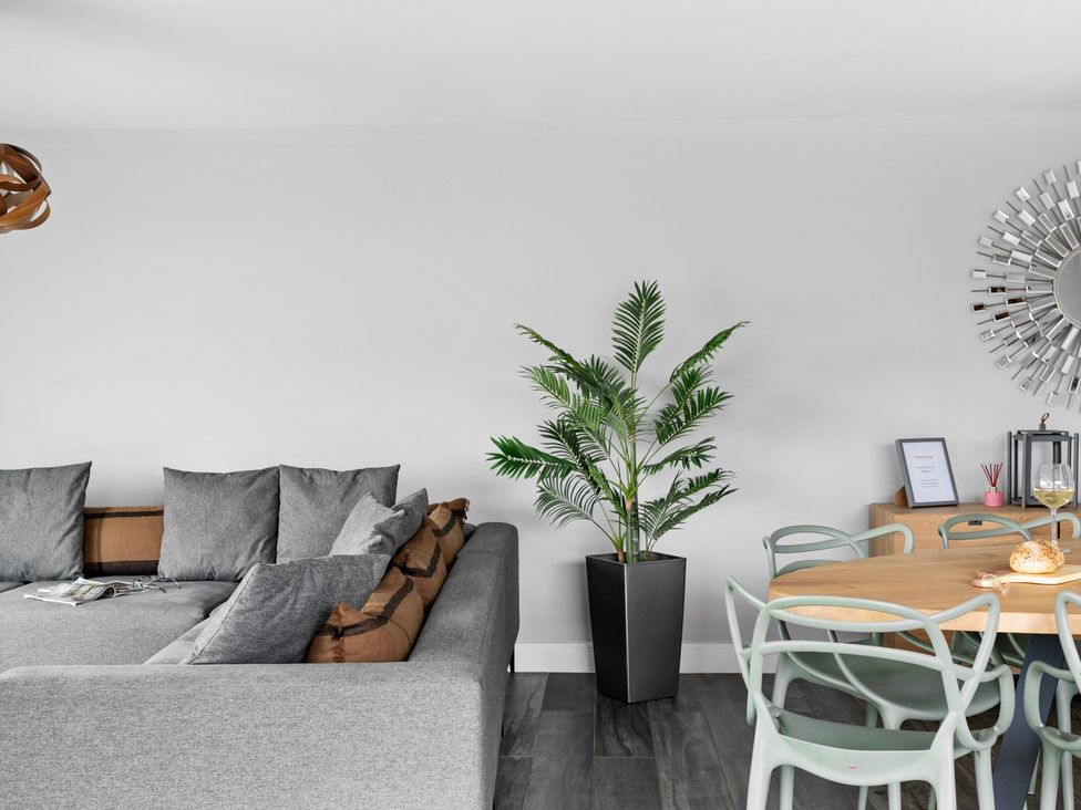 A living room with a grey sectional sofa and a wooden dining table with chairs at Huxham View and Annex in Stoke Canon