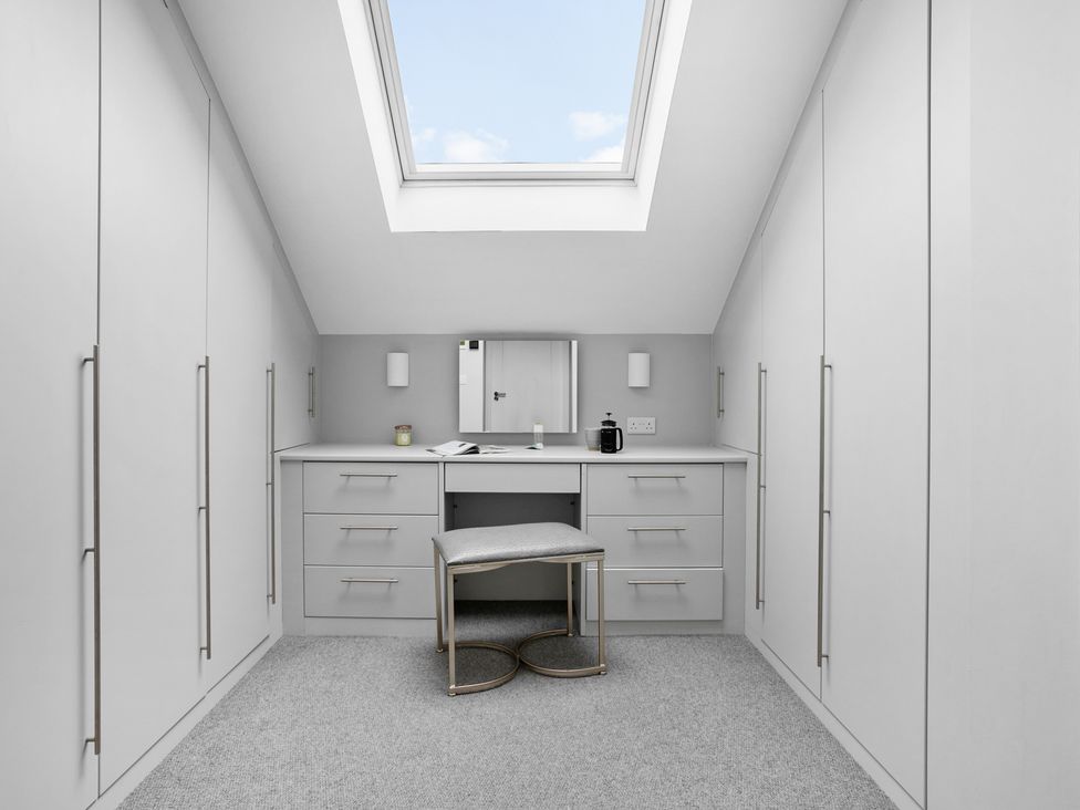 A dressing room with built-in wardrobes and a vanity table under a skylight at Huxham View and Annex in Stoke Canon