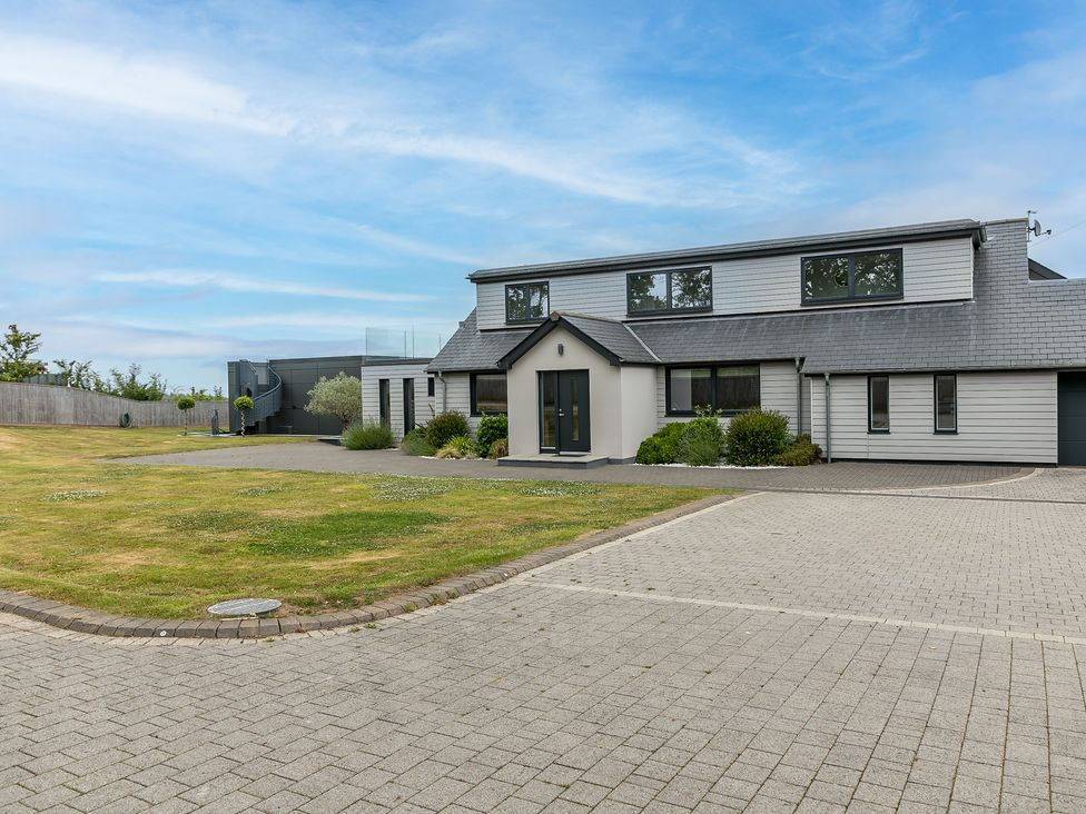 A modern house with a lawn and paved driveway at Huxham View and Annex in Stoke Canon